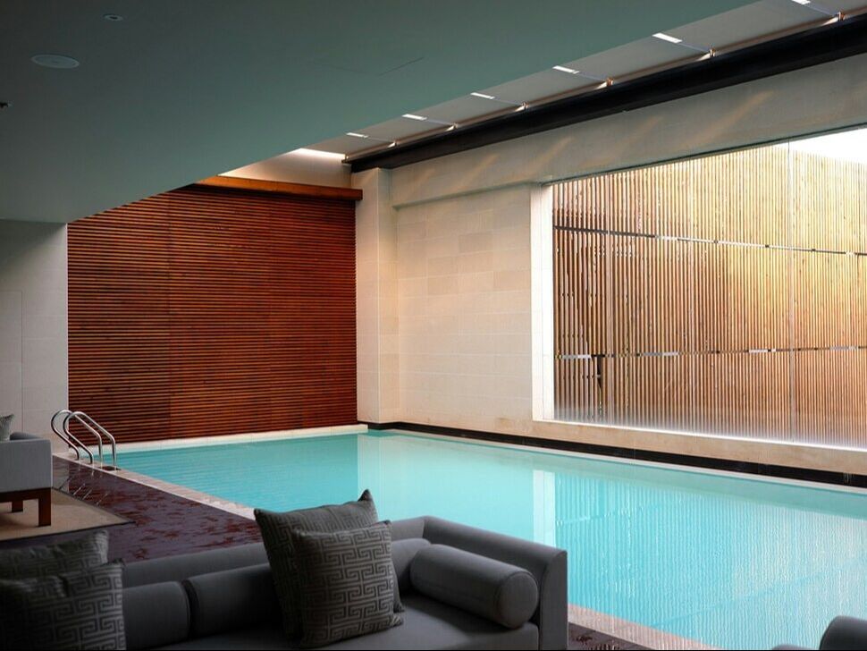 An indoor hotel pool with warm wood panelling and lounge seating