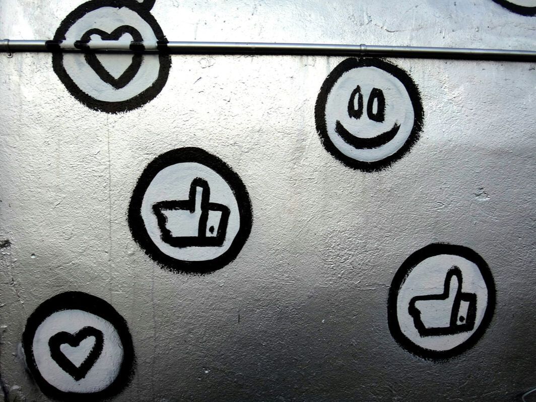 Hand-painted heart, smile and thumbs-up icons on a silver wall
